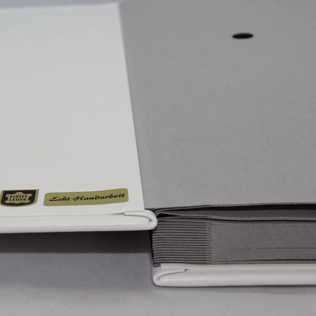Unterschriftenmappe aus glattem Vollrindleder in Weiß, Softcover, dehnbarer Rücken, 20 Register-Trennblätter aus stabiler grauer Kartonage, Aufnahme von DIN A4, Prägungen auf Anfrage